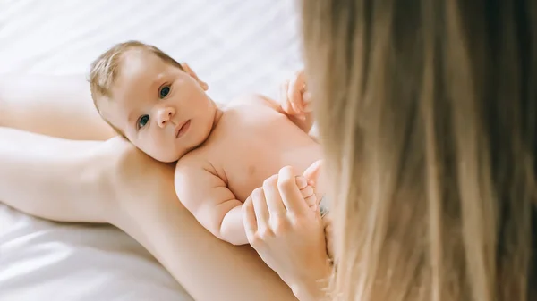 Selective focus of little baby on mother knees in bed at home — Stock Photo