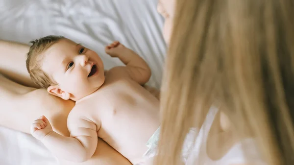 Imagem cortada de mulher brincando com menino adorável na cama em casa — Fotografia de Stock