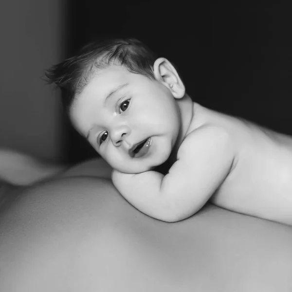 Black and white portrait of baby boy laying on father back — Stock Photo