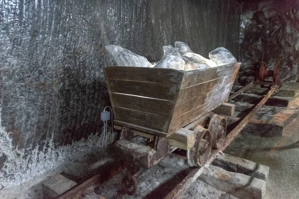 SALINA TURDA, RUMANIA - 4 DE AGOSTO DE 2018: Antigua carreta minera con piedras saladas iluminadas en la mina de sal Salina Turda en Rumania, clasificada entre las 25 joyas ocultas en todo el mundo que valen la pena la caminata —  Fotos de Stock