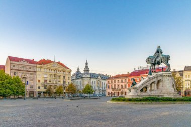 Cluj-Napoca şehir merkezi. Unirii Meydanı'na bir güzel, açık gökyüzü gün gündoğumu, Rhedey Sarayı, Matthias Corvinus anıt ve New York otel görüntülemek.