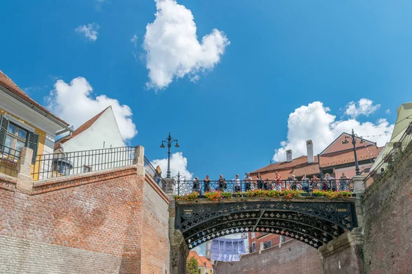Sibiu, Rumunsko - 21. července 2018: Turisté na The Bridge of Lies, jeden z nejvýznamnějších symbolů města a první kovaný Železný most v Rumunsku, za slunečného letního dne s modrou oblohou v Sibiu — Stock fotografie