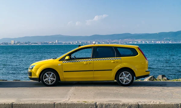 Arka planda su ile görmek bir sokakta sarı taksi arabası. Mavi gökyüzü ile güzel bir güneşli yaz gününde sarı taksi arabası. Sarı taksi arabası bekliyor