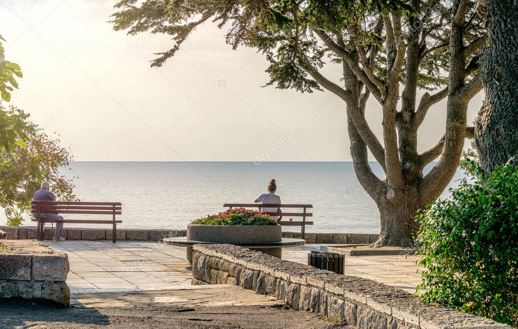 Unidentifiable people on a bench looking peacefully at the see in Nessebar ancient city on the Bulgarian Black Sea Coast. Nesebar or Nesebr is a UNESCO World Heritage Site 