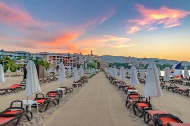 Bulgaristan'ın Karadeniz kıyısında Sunny Beach gün doğumunda güzel bir plajda sandalye ve şemsiye
