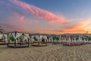 Bulgaristan'ın Karadeniz kıyısında Sunny Beach gün doğumunda güzel bir plajda sandalye ve şemsiye