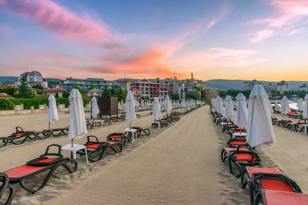 Bulgaristan'ın Karadeniz kıyısında Sunny Beach gün doğumunda güzel bir plajda sandalye ve şemsiye