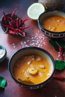 Asty Asya çorba tom yam içinde küçük kaseler, biber biber, tuz ve Hindistan cevizi ve koyu kahverengi zemin üzerine kireç