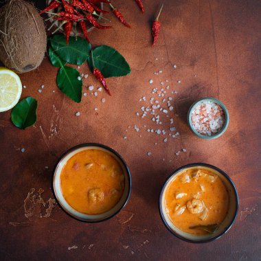 Asty Asya çorba tom yam içinde küçük kaseler, biber biber, tuz ve Hindistan cevizi ve koyu kahverengi zemin üzerine kireç