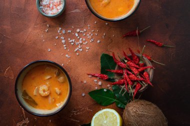 Asty Asya çorba tom yam içinde küçük kaseler, biber biber, tuz ve Hindistan cevizi ve koyu kahverengi zemin üzerine kireç