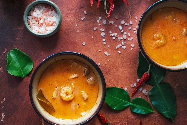 Asty Asya çorba tom yam içinde küçük kaseler, biber biber, tuz ve Hindistan cevizi ve koyu kahverengi zemin üzerine kireç