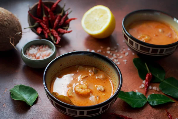 Asty Asya çorba tom yam içinde küçük kaseler, biber biber, tuz ve Hindistan cevizi ve koyu kahverengi zemin üzerine kireç
