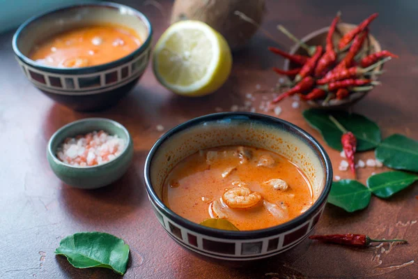 Asty Asya çorba tom yam içinde küçük kaseler, biber biber, tuz ve Hindistan cevizi ve koyu kahverengi zemin üzerine kireç