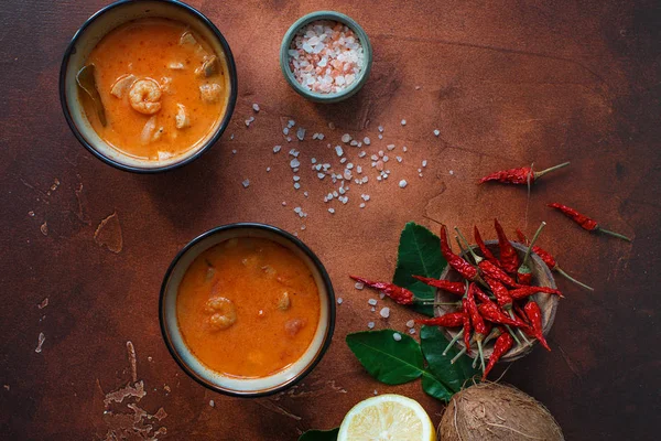 Asty Asya çorba tom yam içinde küçük kaseler, biber biber, tuz ve Hindistan cevizi ve koyu kahverengi zemin üzerine kireç