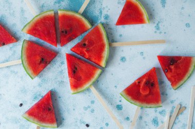 Açık mavi renkli üzerinde taze organik karpuz dilimi popsicles