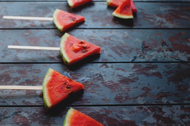 Karanlık bir rustik ahşap arka plan üzerinde taze organik karpuz dilimi popsicles