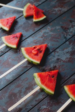 Karanlık bir rustik ahşap arka plan üzerinde taze organik karpuz dilimi popsicles