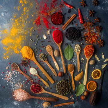 Çeşitli ahşap Hint baharat ve gümüş kaşık ve metal kaseler, tohumlar, otlar ve fındık karanlık taş masada. Renkli baharatlar, üstten görünüm. Organik gıda, sağlıklı yaşam tarzı.