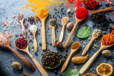 Çeşitli ahşap Hint baharat ve gümüş kaşık ve metal kaseler, tohumlar, otlar ve fındık karanlık taş masada. Renkli baharatlar, seçici odak. Organik gıda, sağlıklı yaşam tarzı.
