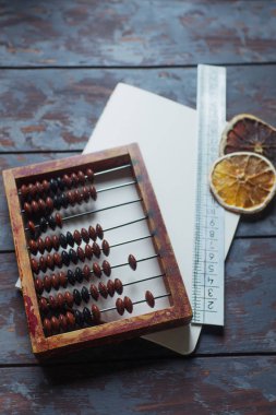 kağıt sayfalarının, cetvel ve rustik ahşap yüzey üzerinde kurutulmuş portakal dilimleri ile Vintage abacus