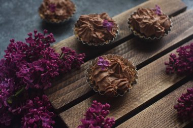 Ahşap ahşap arka plan eflatun çiçekli üzerinde buzlanma çikolata ile ev yapımı vanilyalı kek