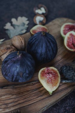 Taze organik incir, fındık ve ahşap tahta ve karanlık taş masa sonbahar yaprakları