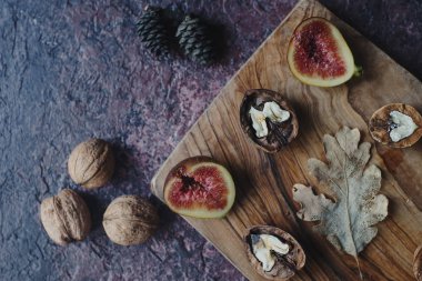 Taze organik incir, fındık ve ahşap tahta ve karanlık taş masa sonbahar yaprakları