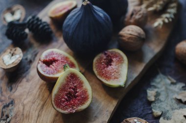 Taze organik incir, fındık ve ahşap tahta ve karanlık taş masa sonbahar yaprakları