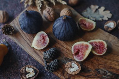 Taze organik incir, fındık ve ahşap tahta ve karanlık taş masa sonbahar yaprakları