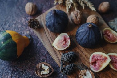 Taze organik incir, fındık ve ahşap tahta ve karanlık taş masa sonbahar yaprakları