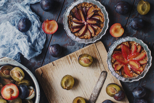 Homemade pies of fresh organic plums on wooden board and rustic table