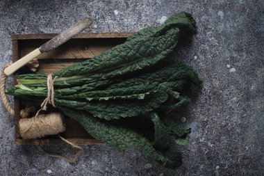 karanlık beton arka plan üzerinde organik Lacinato lahana yaprakları çiğ yeşil üstten görünüm