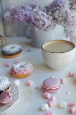 kapuçino, taze renkli çörekler, çilek macaroons ve beyaz mermer masadaki leylak buket Kupası kapatın