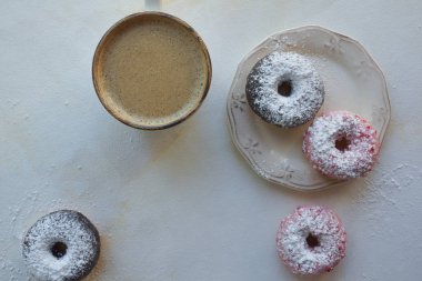 beyaz mermer zemin üzerine taze kahve ve renkli donut Üstten Görünüm