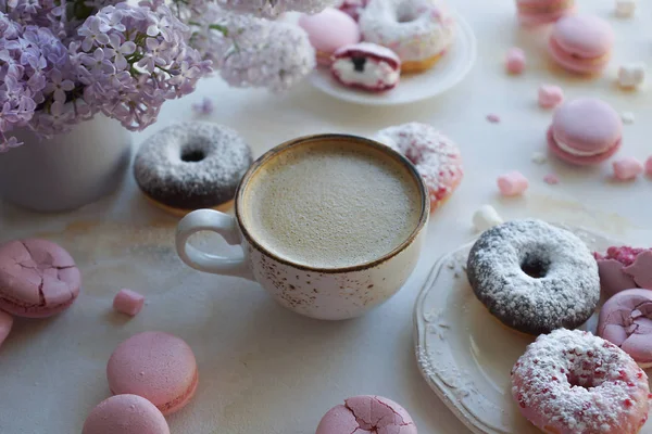 kapuçino, taze renkli çörekler, çilek macaroons ve beyaz mermer masadaki leylak buket Kupası kapatın
