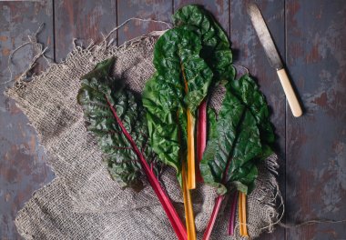 Koyu ahşap masa üzerinde taze organik gökkuşağı İsviçre pazı yaprakları, renkli sağlıklı gıda konsepti