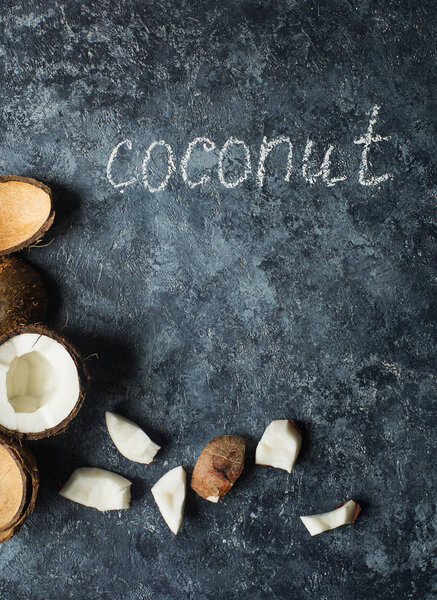Fresh raw halved coconut fruits on dark stone background, broken coconut, healthy lifestyle concept 