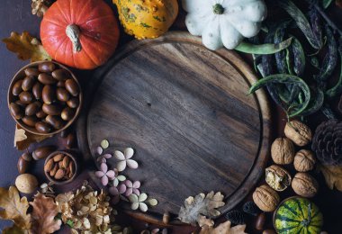 Dekoratif kabak, meşe palamudu, fındık, yeşillik, sonbahar yaprakları ve metin için alan ile ahşap tahta ile Sonbahar arka plan