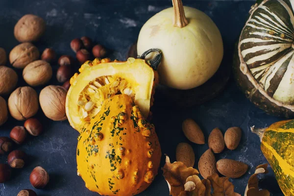 Fondo de otoño o de acción de gracias con calabaza decorativa, maíz, nueces, uvas y trigo en la mesa de piedra oscura — Foto de Stock