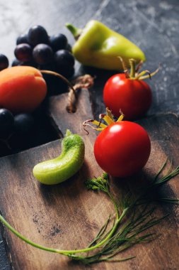 Köy ahşap kesim tahtasının etrafında çiğ taze meyve ve sebzeler. 