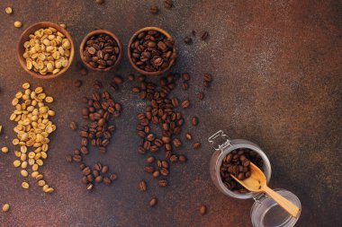 Üç çeşit taze kavrulmuş kahve çekirdeği. Koyu taş arka planda kâselerde.