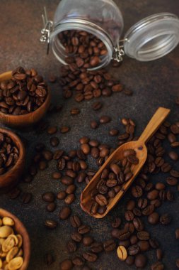 Taze kavrulmuş kahve çekirdekleri ve koyu taş arka planda ahşap kepçe.