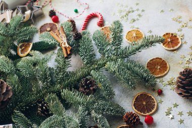 Noel veya yeni yıl süslemesi, köknar ağacı, şeker kamışı, kuru portakal, koni ve kurabiye keskisi beyaz taş arka planda 