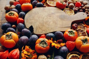 Taze meyve ve sebzeli sonbahar natürmortu. Erik, hurma, ceviz, ayçiçeği, kuru portakal ve kırsal ahşap tahta çeşitleri, seçici odak, metin için alan