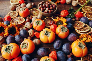 Taze organik meyve ve sebzelerle sonbahar natürmortu kompozisyonu. Erik, hurma, ceviz, ayçiçeği ve kuru portakal çeşitleri, seçici odak