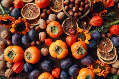 Taze organik meyve ve sebzelerle sonbahar natürmortu kompozisyonu. Erik, hurma, ceviz, ayçiçeği ve kuru portakal çeşitleri.