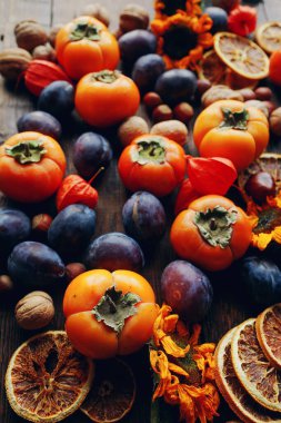 Taze organik meyve ve sebzelerle sonbahar natürmortu kompozisyonu. Erik, hurma, ceviz, ayçiçeği ve kuru portakal çeşitleri, seçici odak