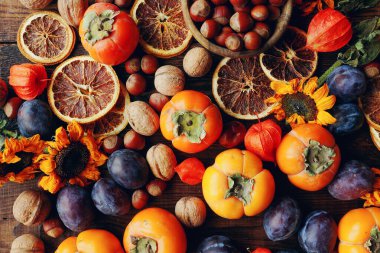 Taze organik meyve ve sebzelerle sonbahar natürmortu kompozisyonu. Erik, hurma, ceviz, ayçiçeği ve kuru portakal çeşitleri.