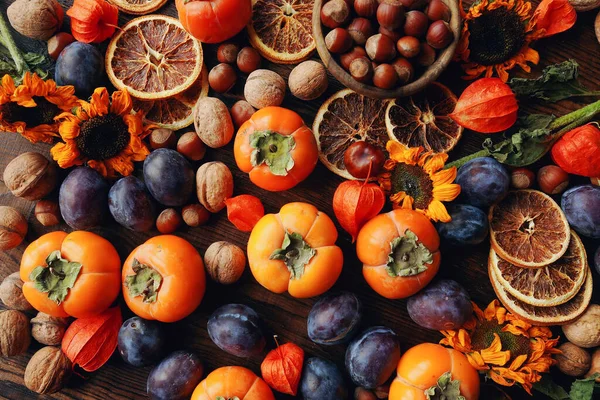 Taze organik meyve ve sebzelerle sonbahar natürmortu kompozisyonu. Erik, hurma, ceviz, ayçiçeği ve kuru portakal çeşitleri.