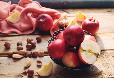 Sıcak sonbahar kompozisyonu taze organik elmalar ve fındıklar kırsal ahşap masa üzerinde, seçici odaklanma